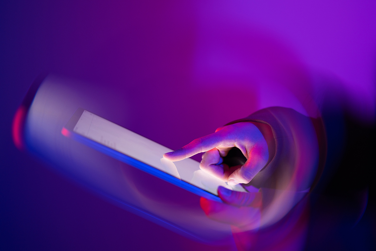 Gemini 2.0 : Mão interagindo com uma tela sensível ao toque em um cenário de luzes de neon.